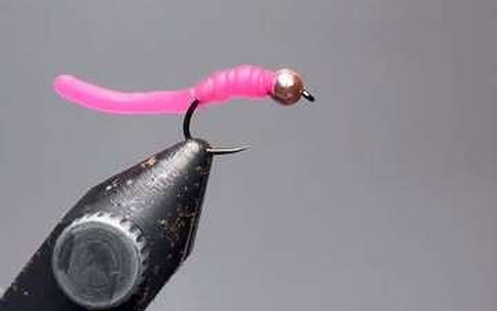 A jig-head pink Squirmy Worm held in vise jaws